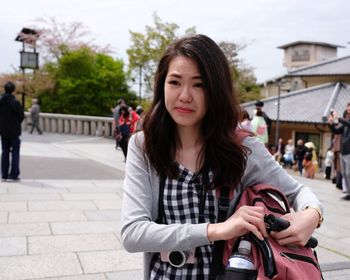 Portrait of beautiful young woman standing on street in city