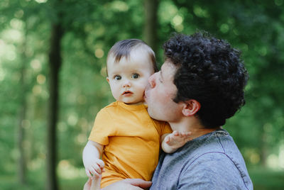 Portrait of one father holding his little  daughter in his arms and kissing her on the cheek