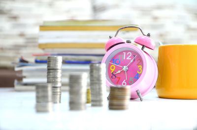 Stacked coins and alarm clock on desk