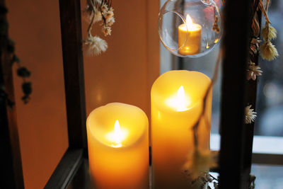 Close-up of lit candles on glass at home