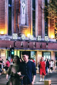 People walking on illuminated street in city at night