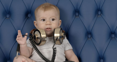 Portrait of cute boy with headphones sitting on sofa