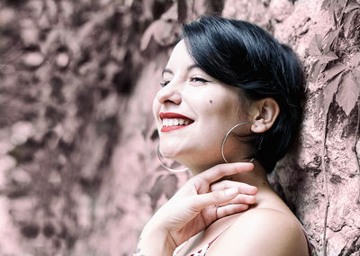 Smiling young woman looking away against rock