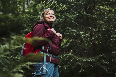 Woman with backpack hiking in forest, actively spending summer vacation close to nature
