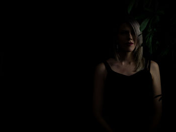 Young woman standing against black background