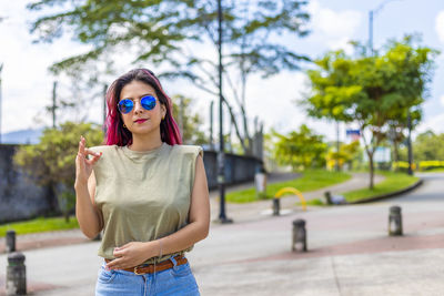 Portrait of woman wearing sunglasses standing against trees