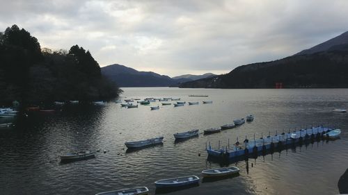 Boats in lake against cloudy sky