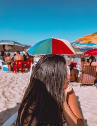 Young woman looking away while sitting at beach