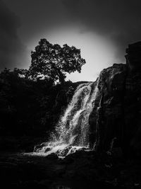 Scenic view of waterfall against sky