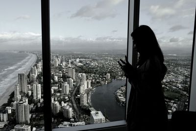 Woman standing by window in city