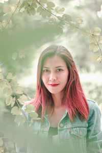 Portrait of beautiful young woman against tree