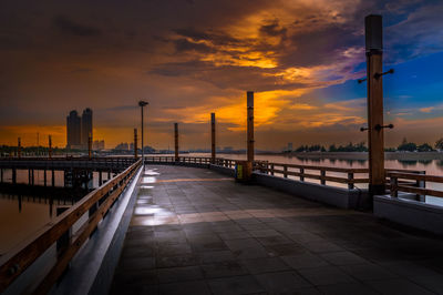 Footpath by bridge against sky during sunset