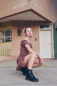 Portrait of woman sitting against building