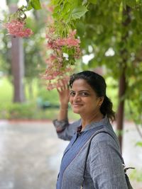 Portrait of young woman standing against trees