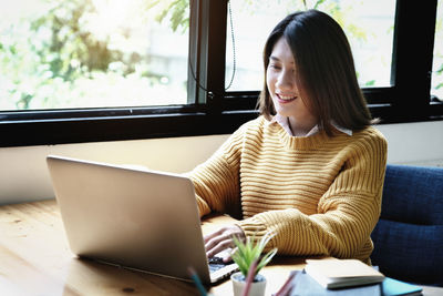 Young woman using phone while sitting on table