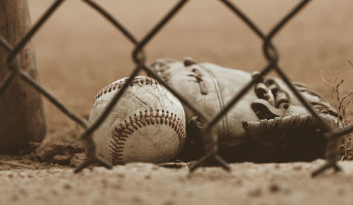 Close-up of ball on land seen through chainlink fence
