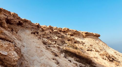 Low angle view of rock formation against clear blue sky