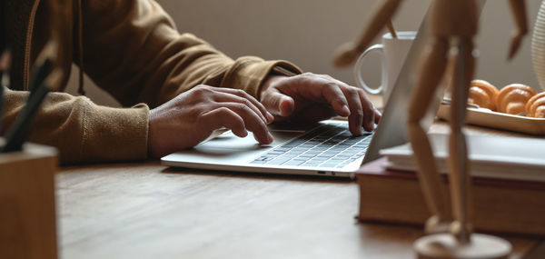 Midsection of man using mobile phone on table