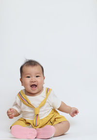 Cute boy sitting against white background