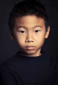 Close-up portrait of boy against black background