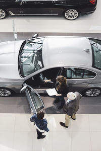 High angle view of saleswoman showing car to customers at showroom
