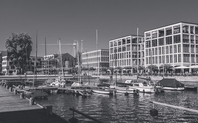 Boats moored at harbor against clear sky