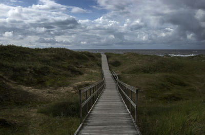 Footbridge over sea against sky