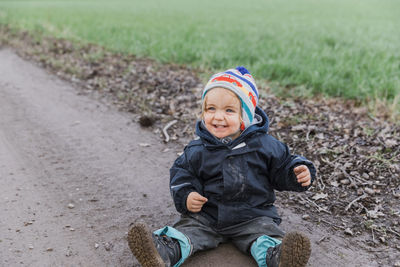 Smiling girl sitting on dirt road during winter