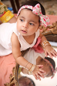 Cute baby girl wearing headband while looking away at home