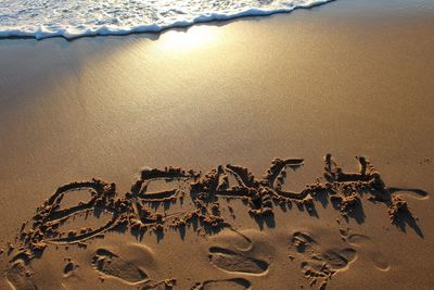 High angle view of text on sandy beach during sunset