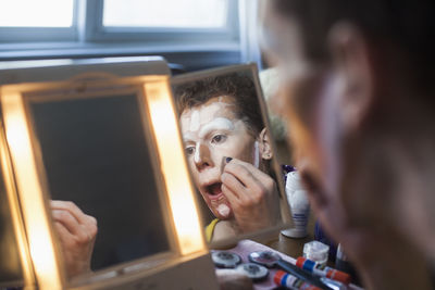 Man applying drag makeup in mirror