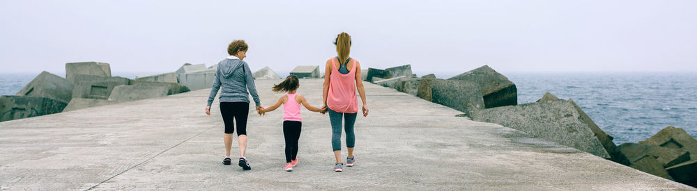 Rear view of family walking on pier