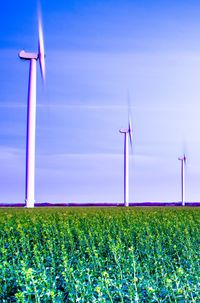 Wind turbines on field against sky