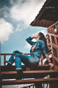 Low angle view of woman sitting on chair against sky