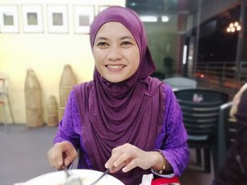 Portrait of smiling young woman sitting in restaurant