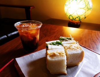 Close-up of sandwich with drink served on wooden table