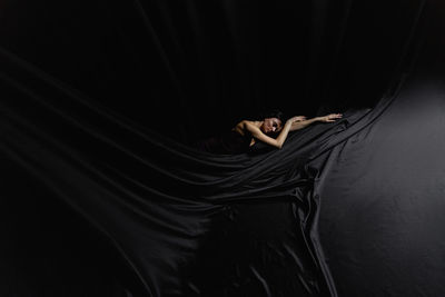 Low angle view of woman standing against black background