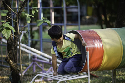 Boy playing on outdoor play equipment in playground