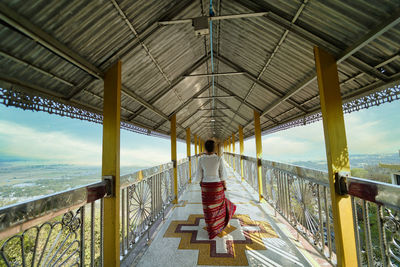 Rear view of woman standing by railing on sea