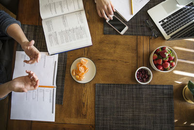 Overhead view of young man studying on wooden table at home