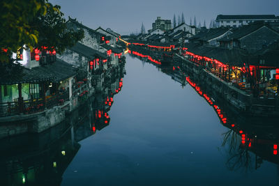 River amidst illuminated houses in town