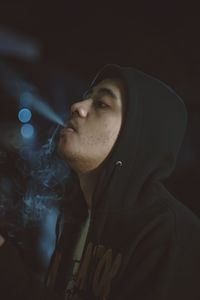 Close-up of man exhaling smoke at night