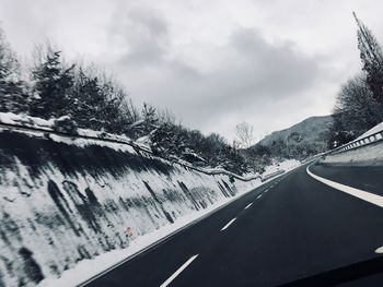 Road by snow covered mountain against sky