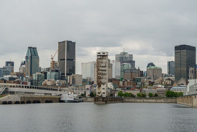 Modern buildings by river against sky in city