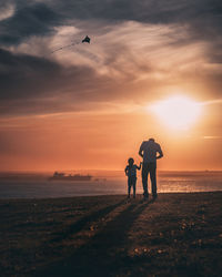 Rear view of father and daughter standing on shore at beach