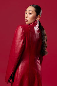 Portrait of young woman standing against yellow background