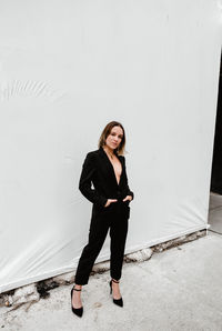 Portrait of young woman standing against wall