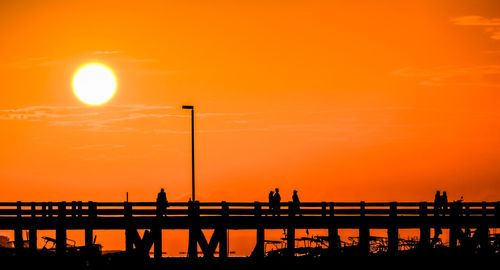 Silhouette people on pier against sky during sunset