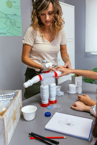 Teacher helping to children make recycled toy robot with plastic packages