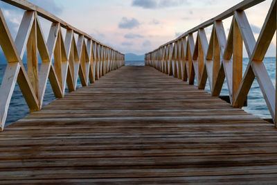 Surface level of wooden footbridge against sky